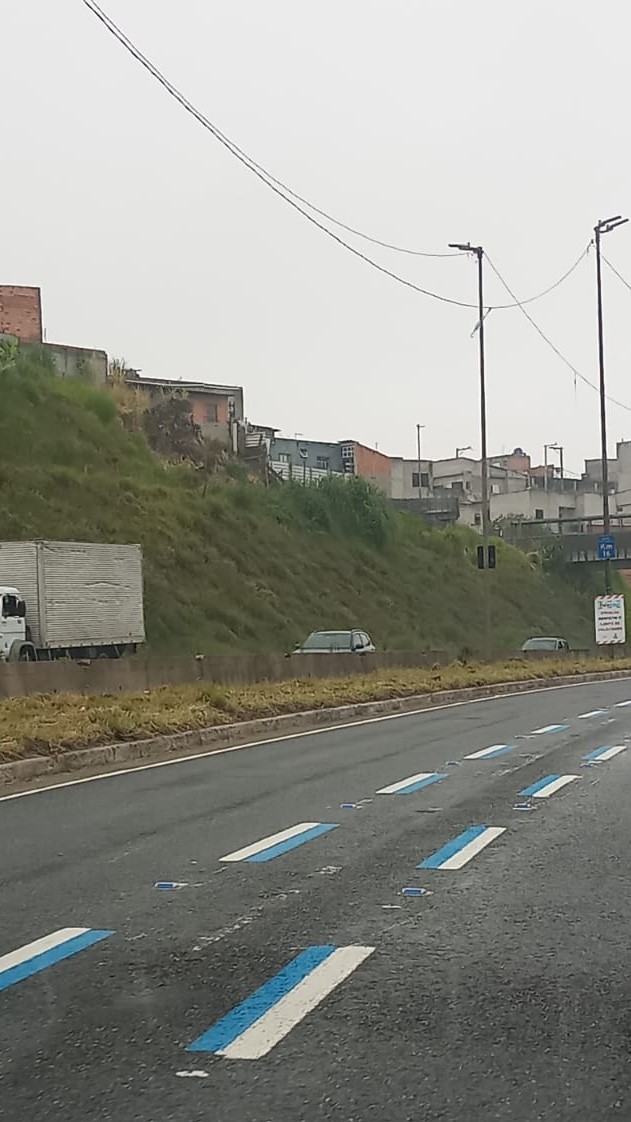 Em uma avenida, faixa estreita está marcada com cores azul e branco. 